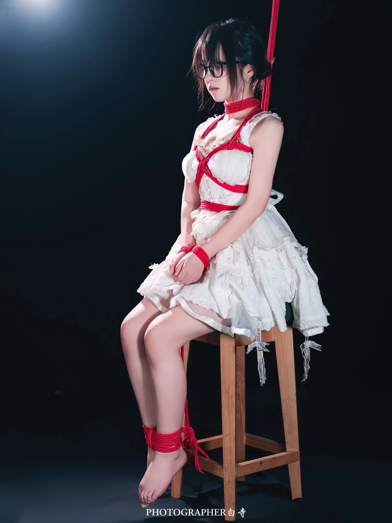 穿着白色衣服的女人被绑在椅子上。