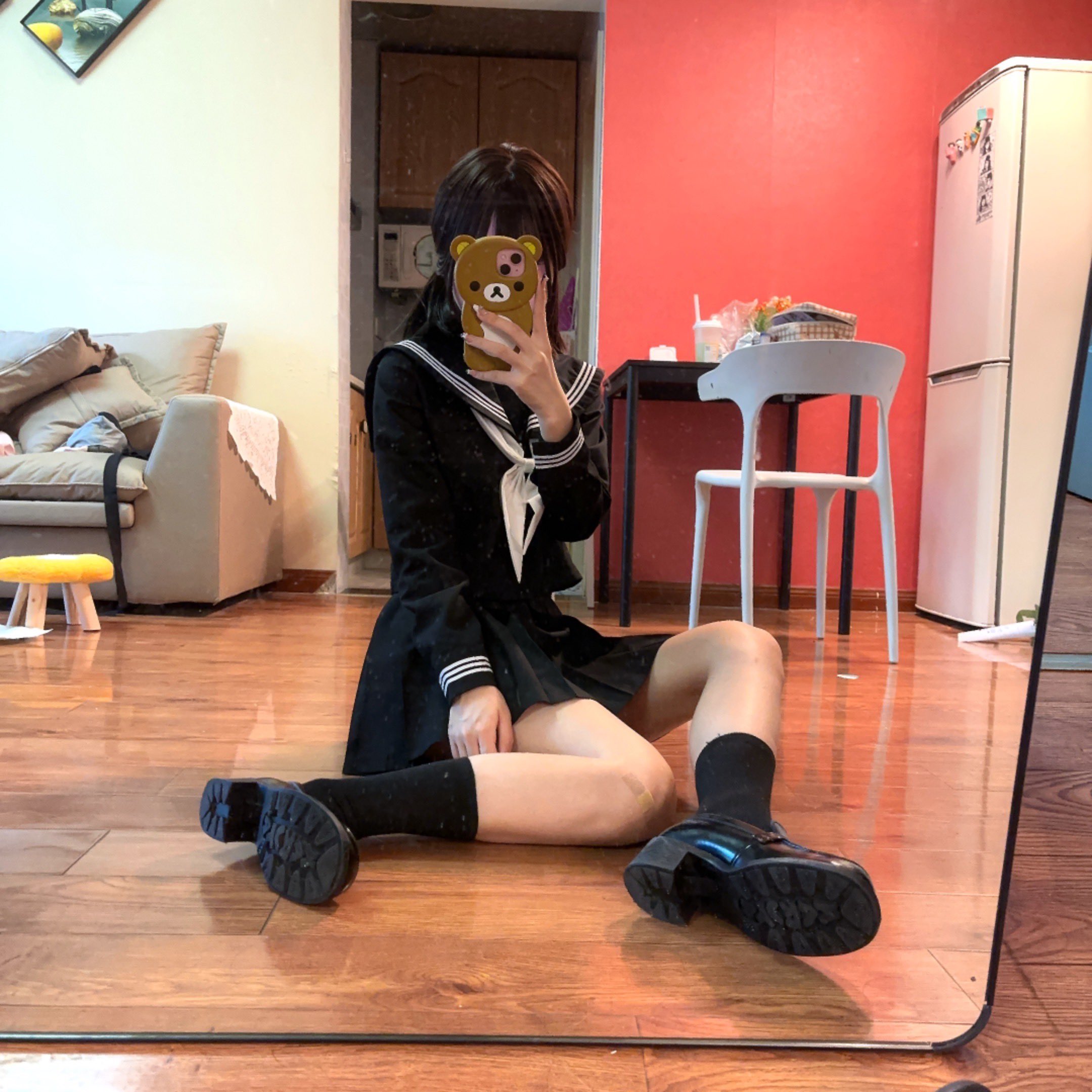 一位穿着黑色裙子和白色项链的女人在镜子前拍摄自拍。