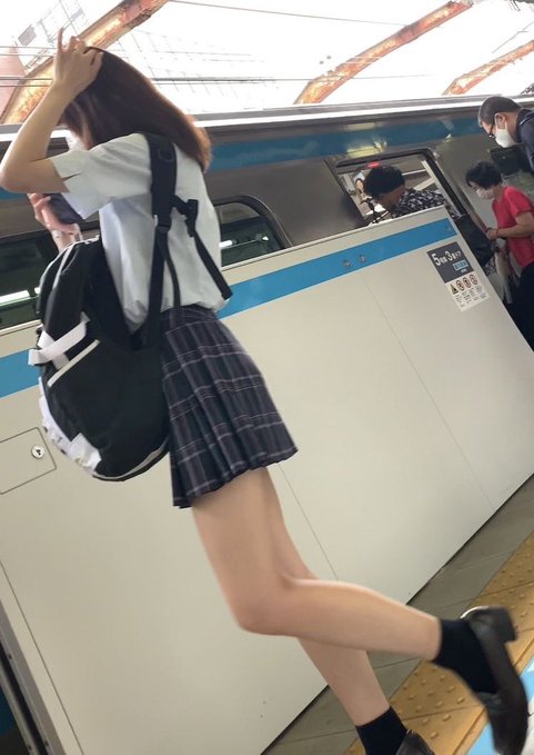 一位穿着蓝色衬衫和一件白色的裙子的女人走在街上。