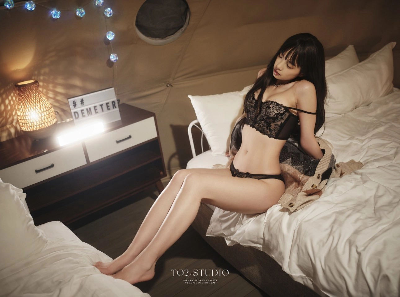 穿着黑色裤子和裤子的女人坐在床上。