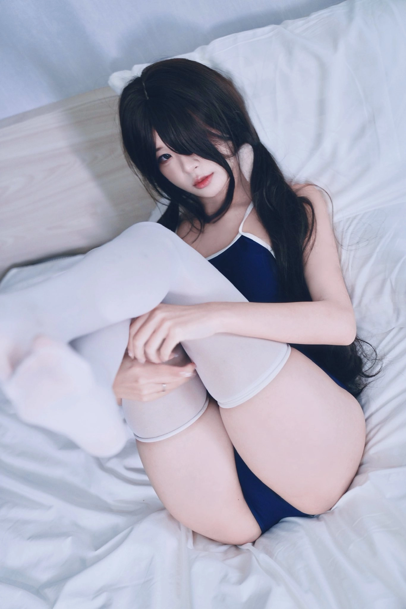 一位穿着蓝色裙子和白色裤子的女人躺在床上。