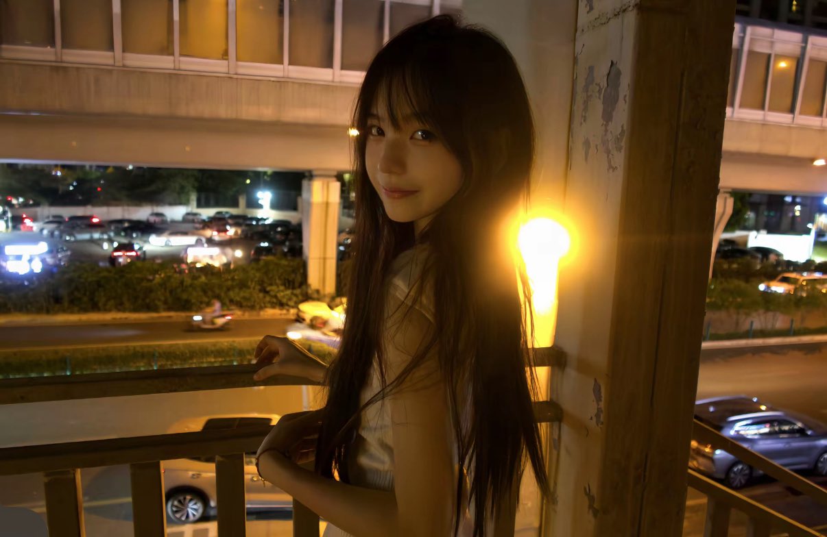 长头发和一件白色衬衫的女人站在阳台上。