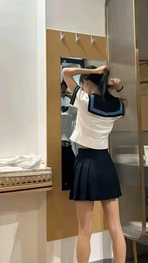 一位穿着蓝色和白色的女士在镜子前调整她的头发。