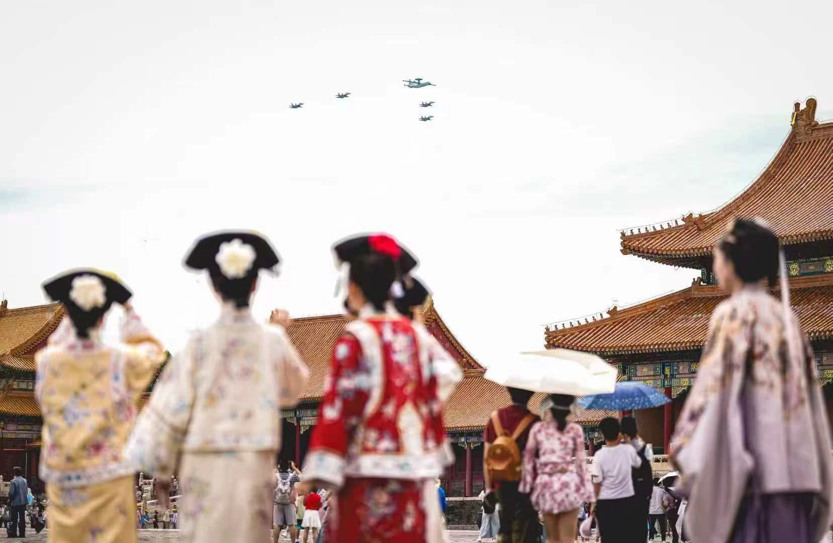 一群人看着飞机飞越头顶。