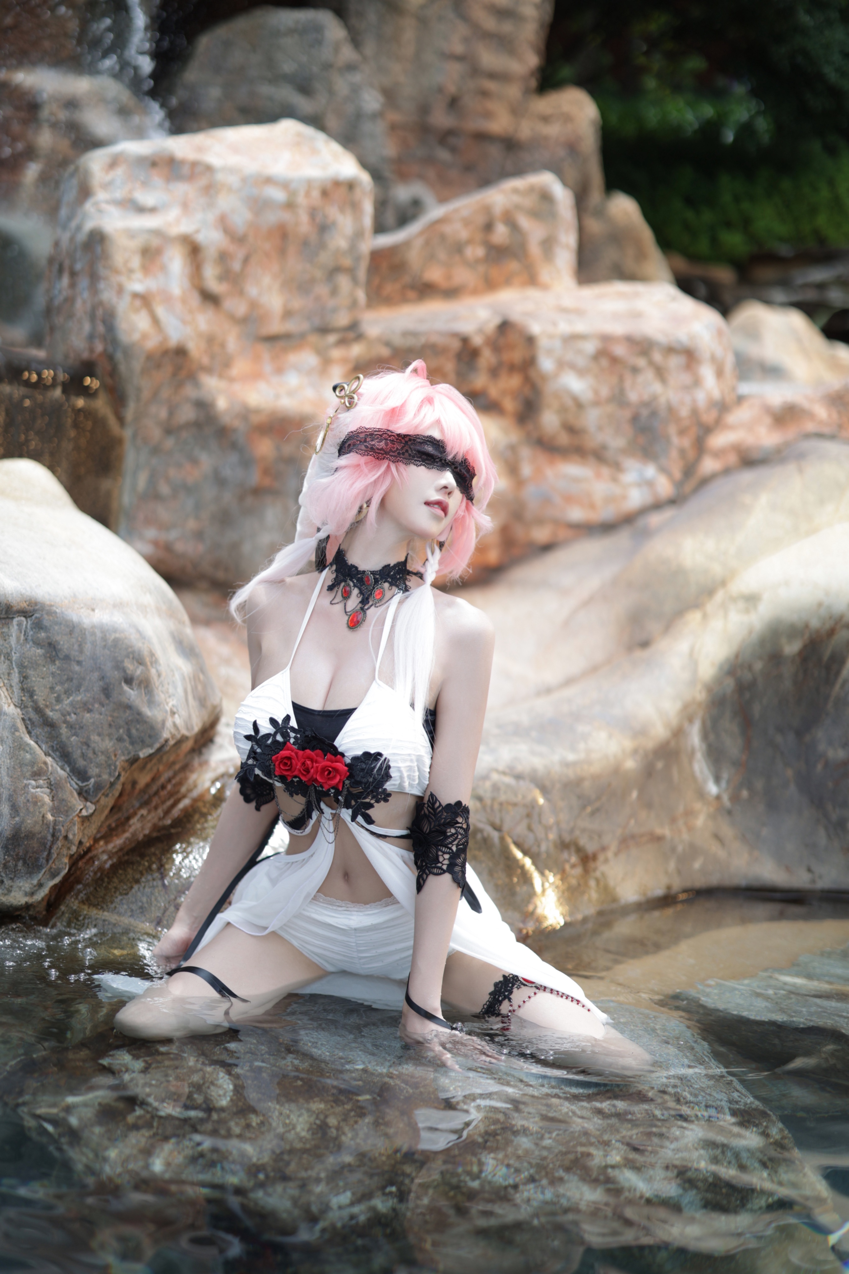 一位穿着一件白色裙子的女人,戴着一根黑色的绳子,坐在一条河流里。