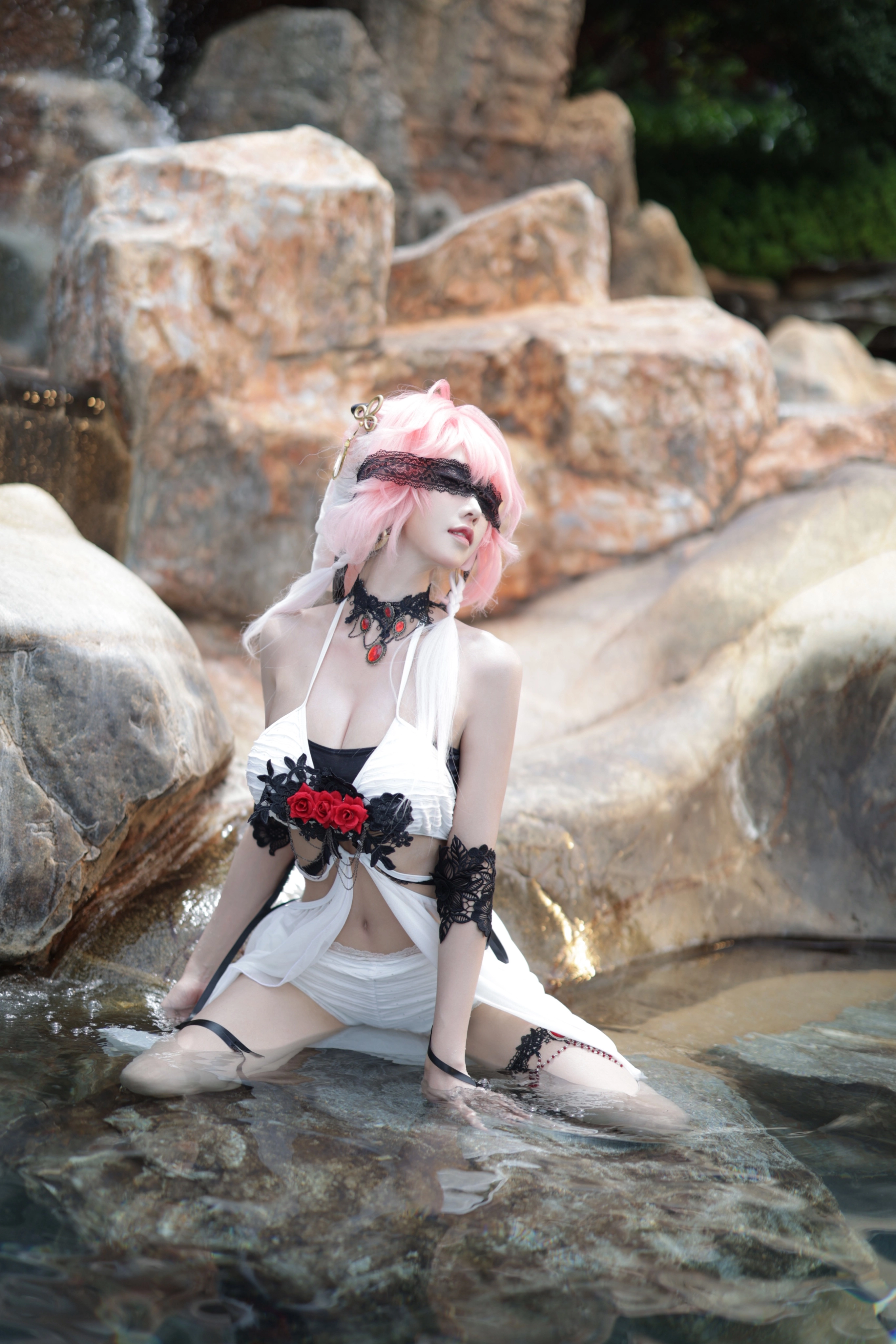 一位穿着一件白色裙子的女人,戴着一根黑色的绳子,坐在一条河流里。