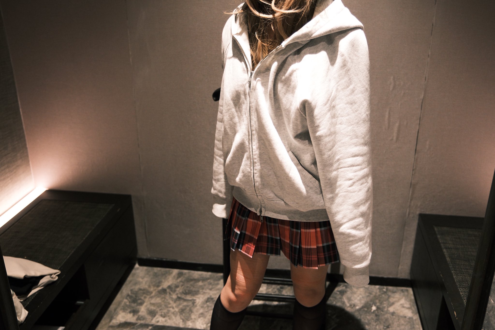 女人穿着一件白色的胡迪和一件白色的裙子。