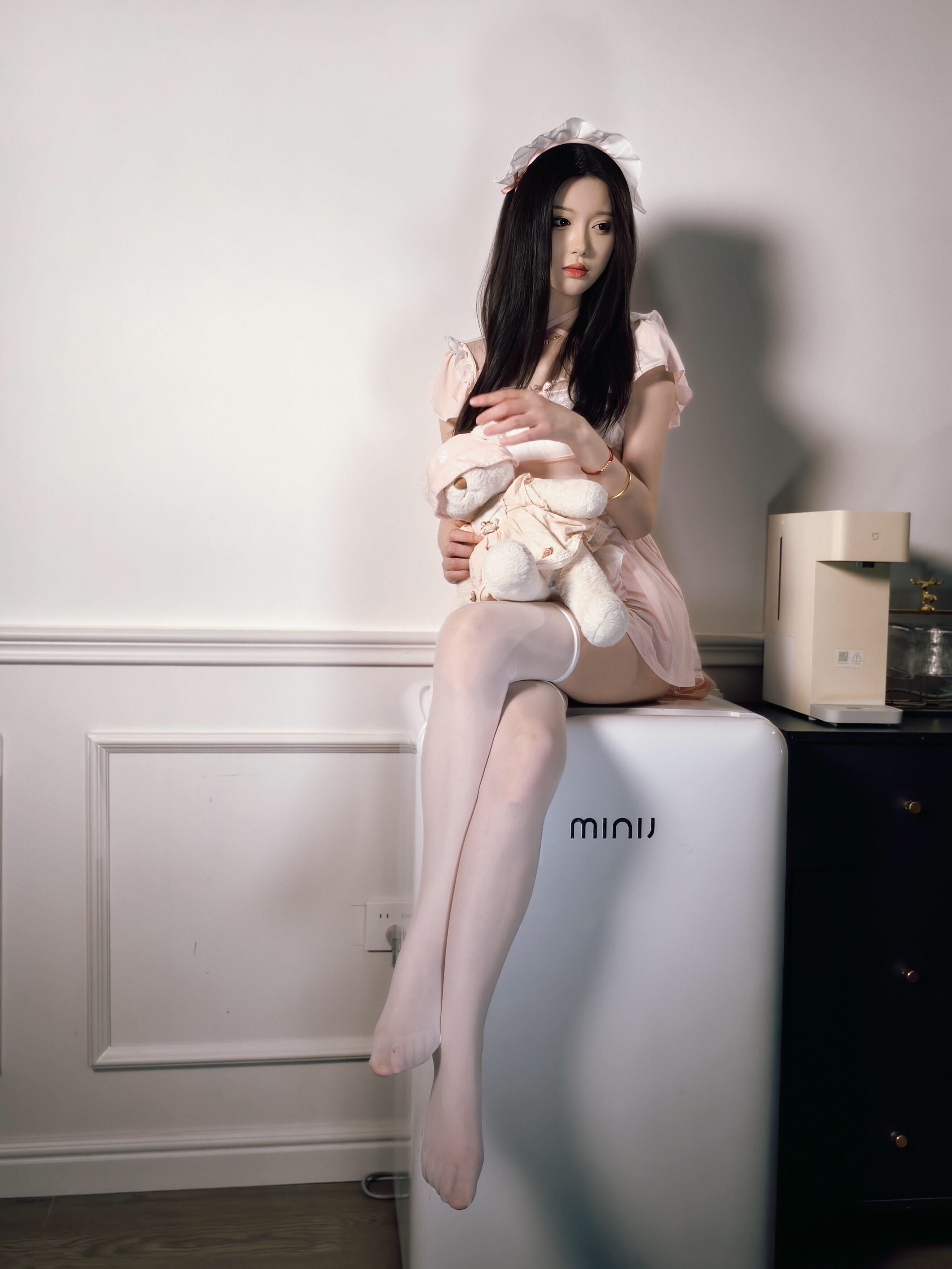 穿着白色裙子和裤子的女人坐在冰箱的顶部。