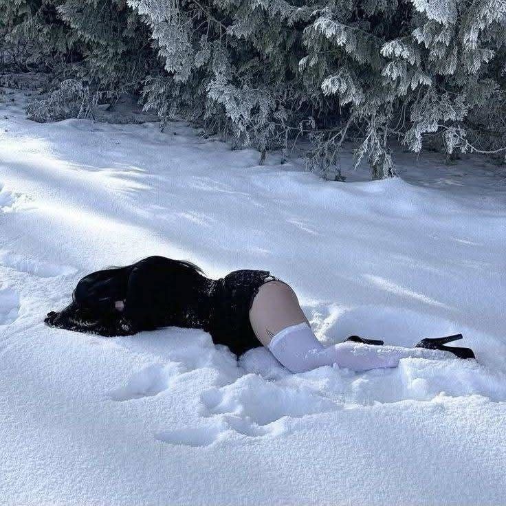 穿着黑色衣服的女人躺在雪地里。