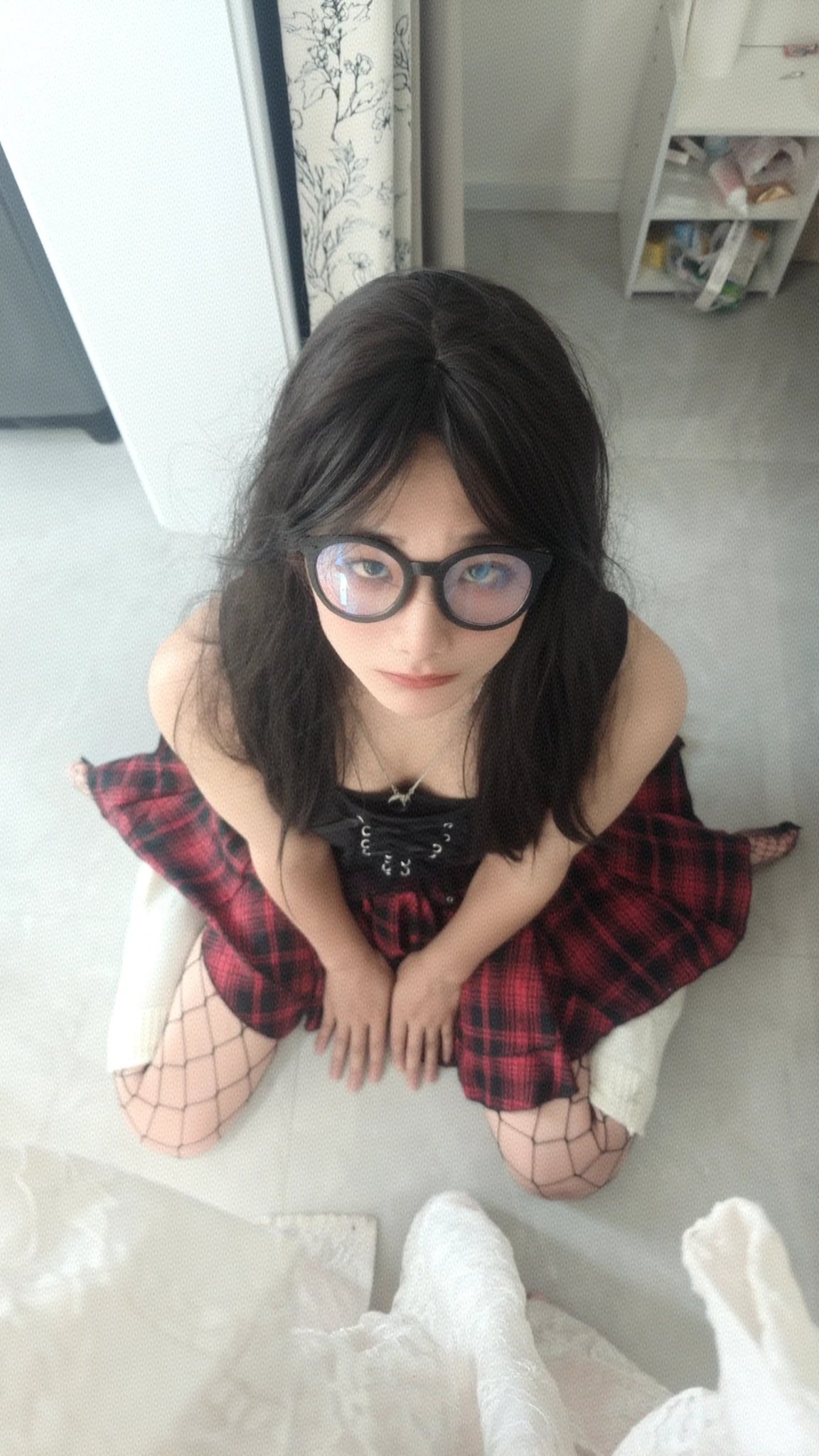 戴着眼镜和一件黑色衣服的女人坐在地板上。