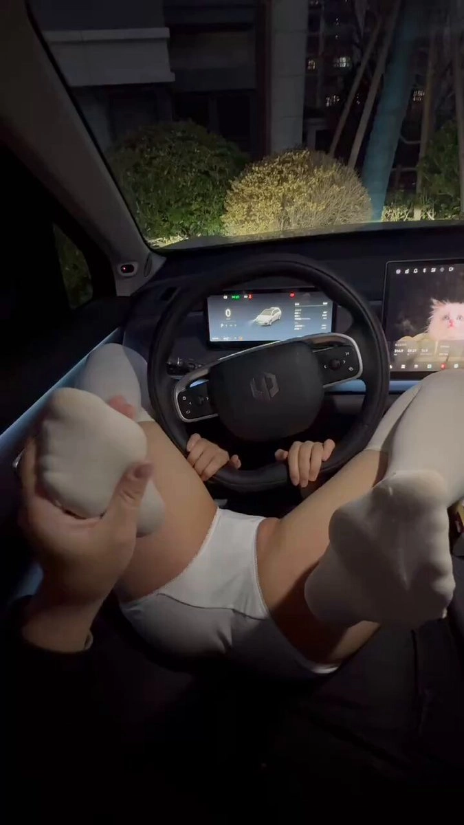 女人坐在车里,她的腿在车轮上。