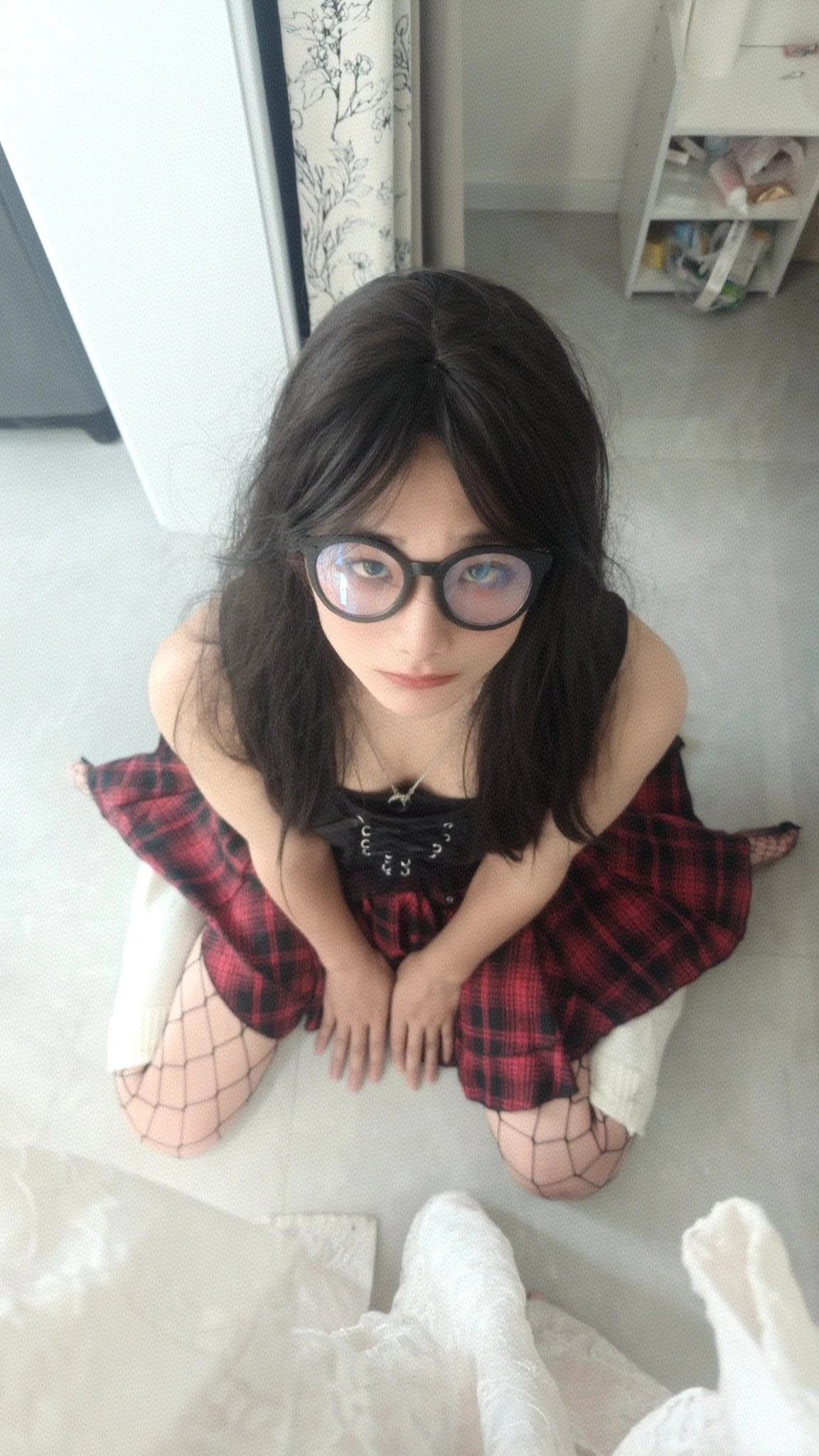 戴着眼镜和一件黑色衣服的女人坐在地板上。