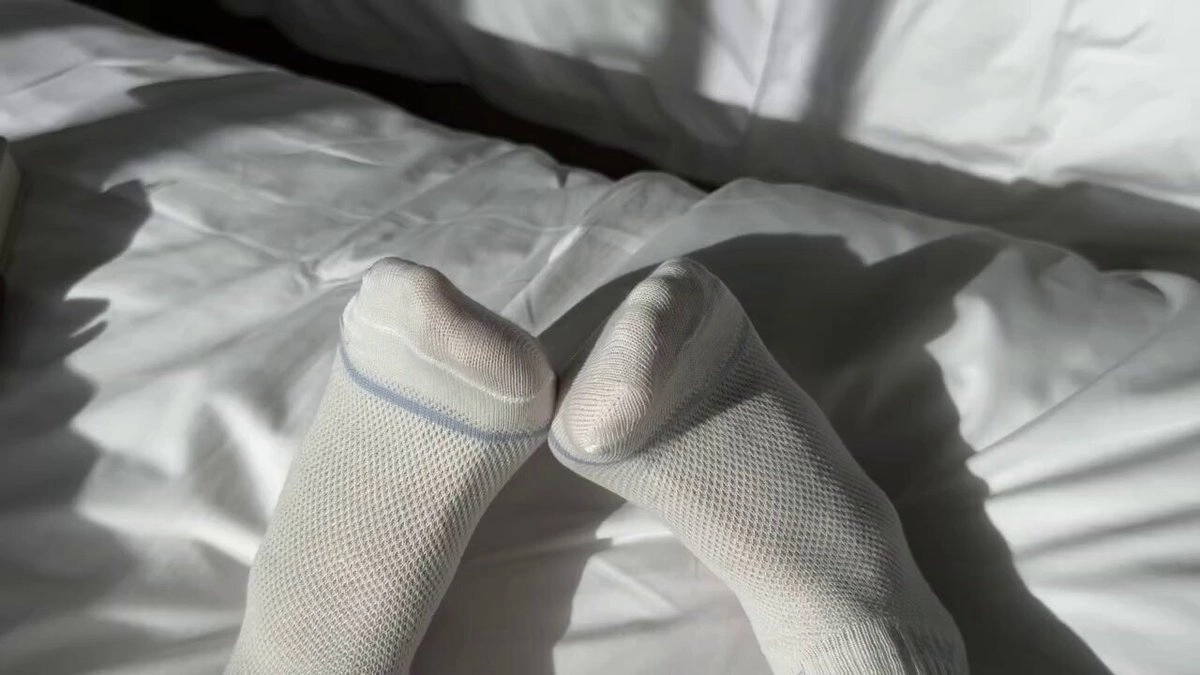 一双白色袜子在床上。