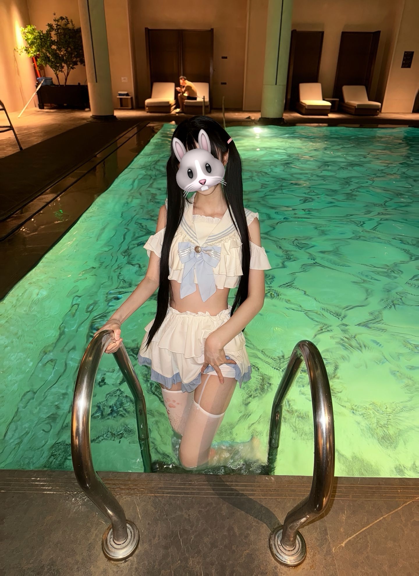一位穿着兔子面具和水手服的女人在游泳池里。