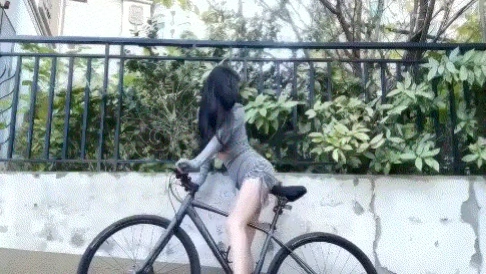 女人骑自行车,她的头发在一个马尾巴。