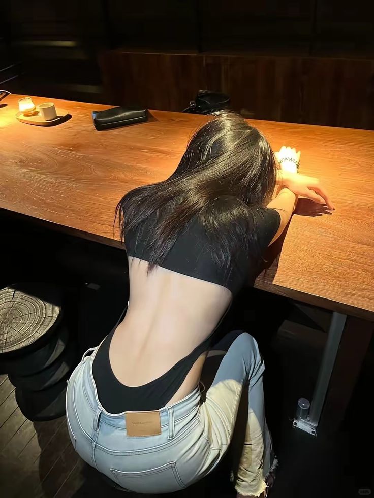 穿着黑色衬衫和蓝色裤子的女人坐在一张桌子上。