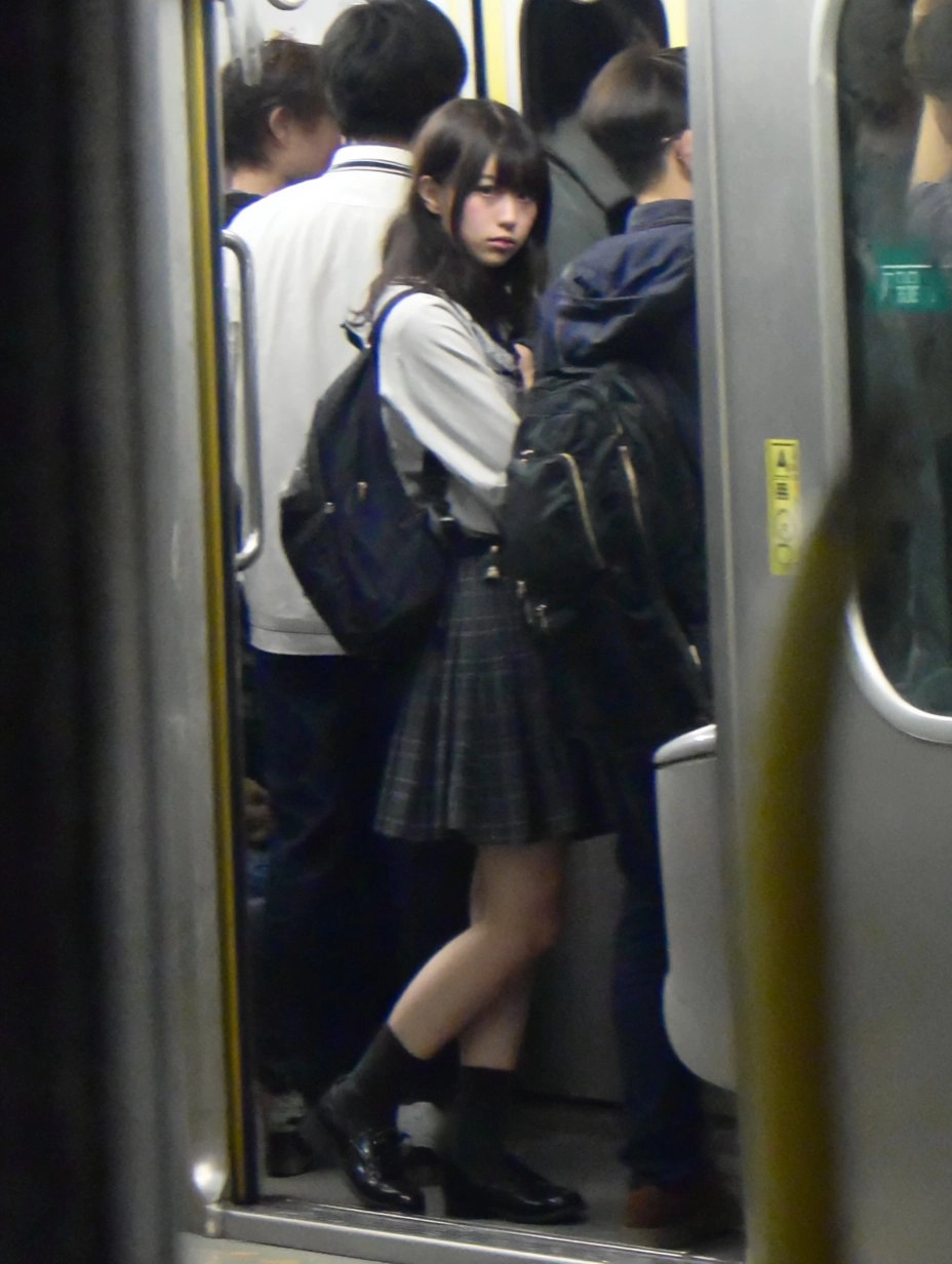 一位穿着裙子和黑靴的女人站在地铁平台上。