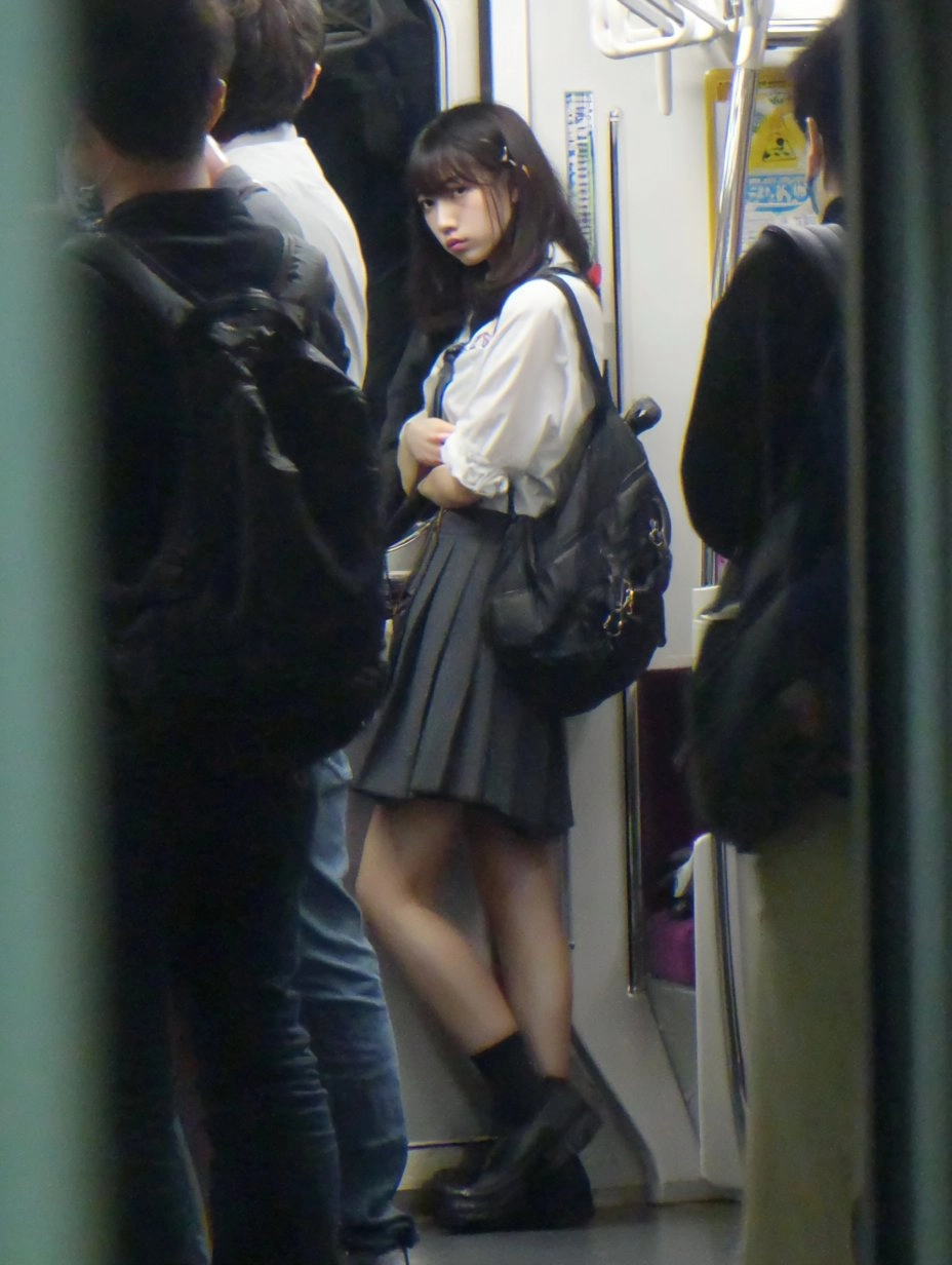 一位穿着裙子和白衬衫的女人站在地铁平台上。