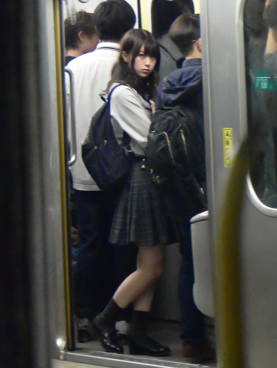 一位穿着裙子和黑靴的女人站在地铁平台上。