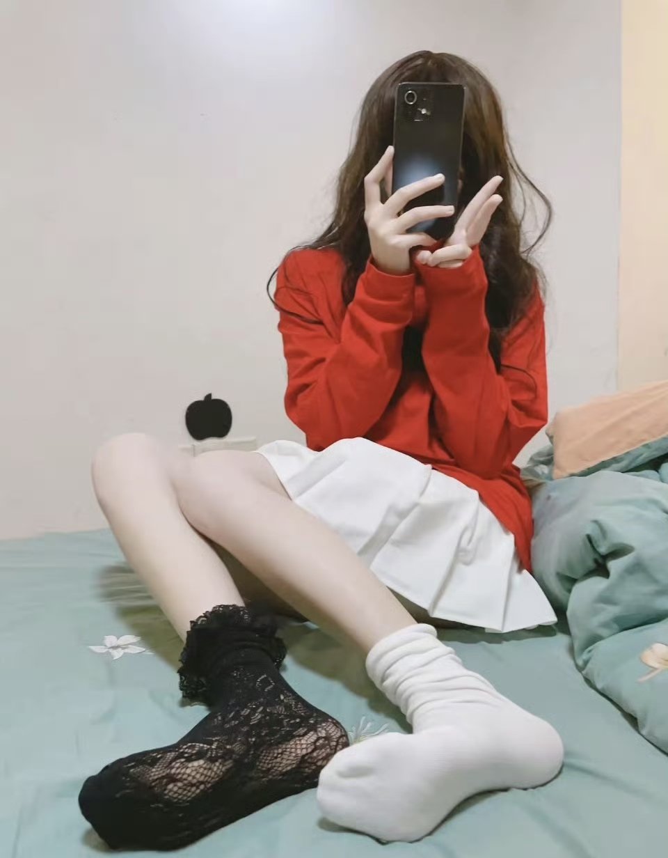 一位穿着红色衬衫和白色裙子的女人用手机拍自拍。