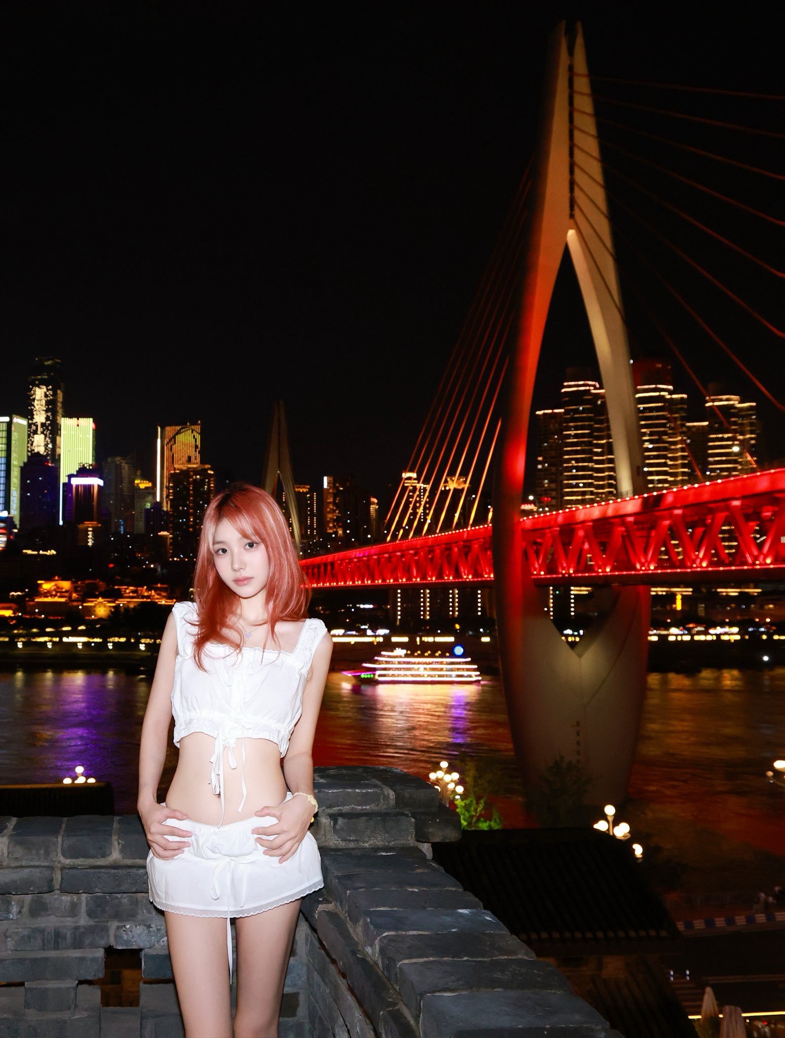 一位穿着白色衣服的女人晚上站在一座桥上。