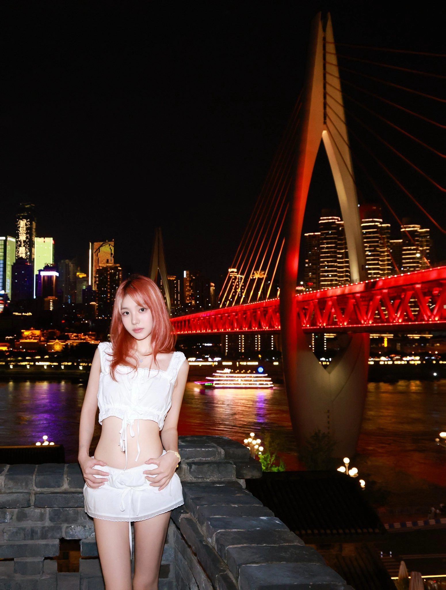 一位穿着白色衣服的女人晚上站在一座桥上。