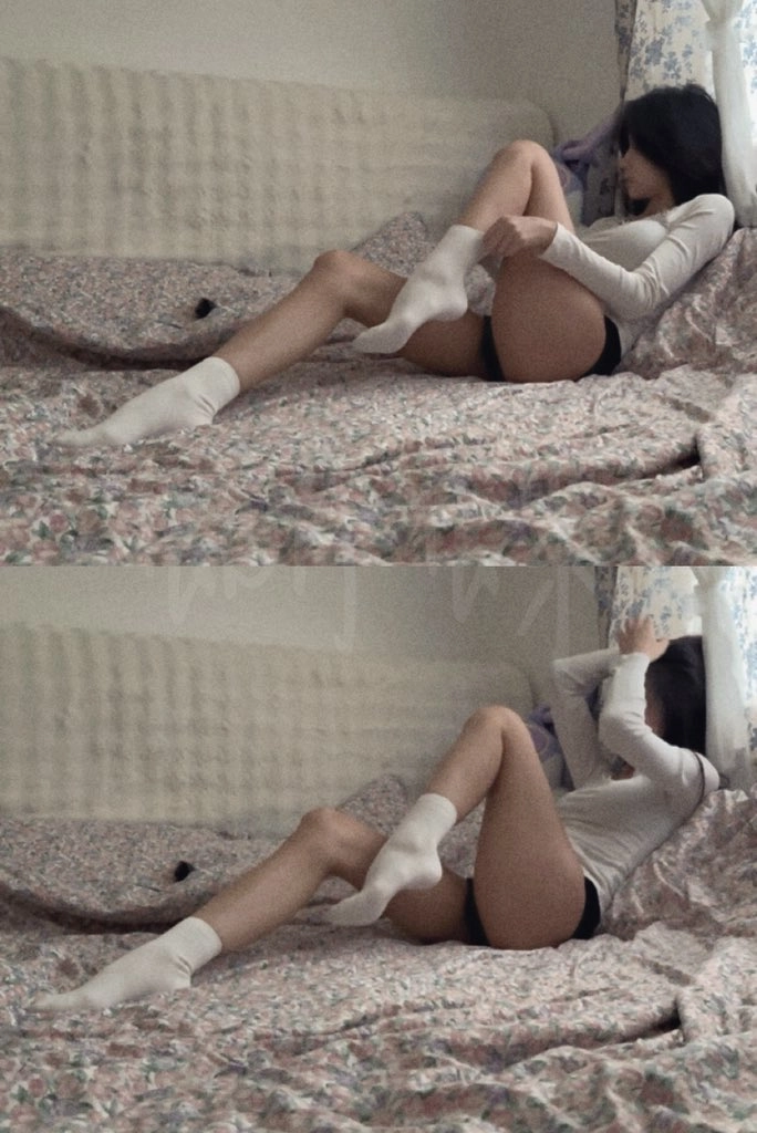 一位穿着白色衬衫和黑色短裤的女人躺在床上。