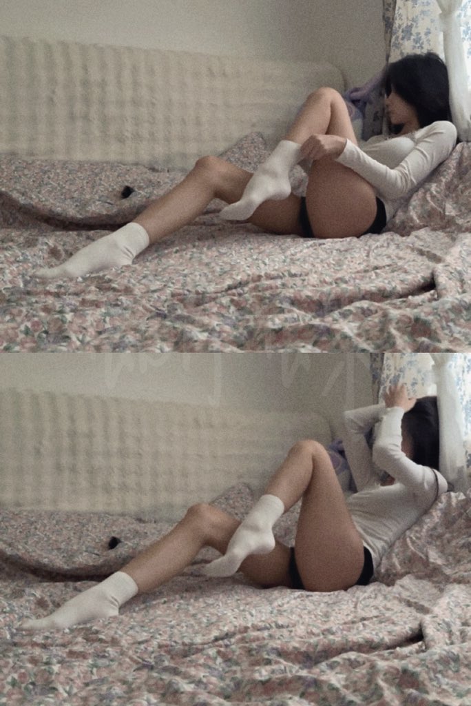 一位穿着白色衬衫和黑色短裤的女人躺在床上。