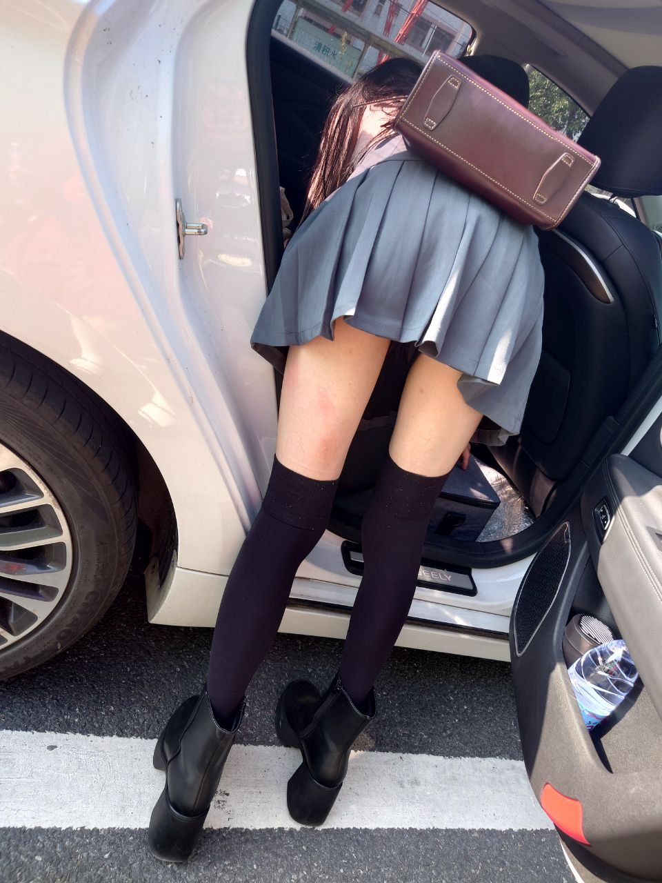 穿着灰色裙子和黑色靴子的女人正在车上。