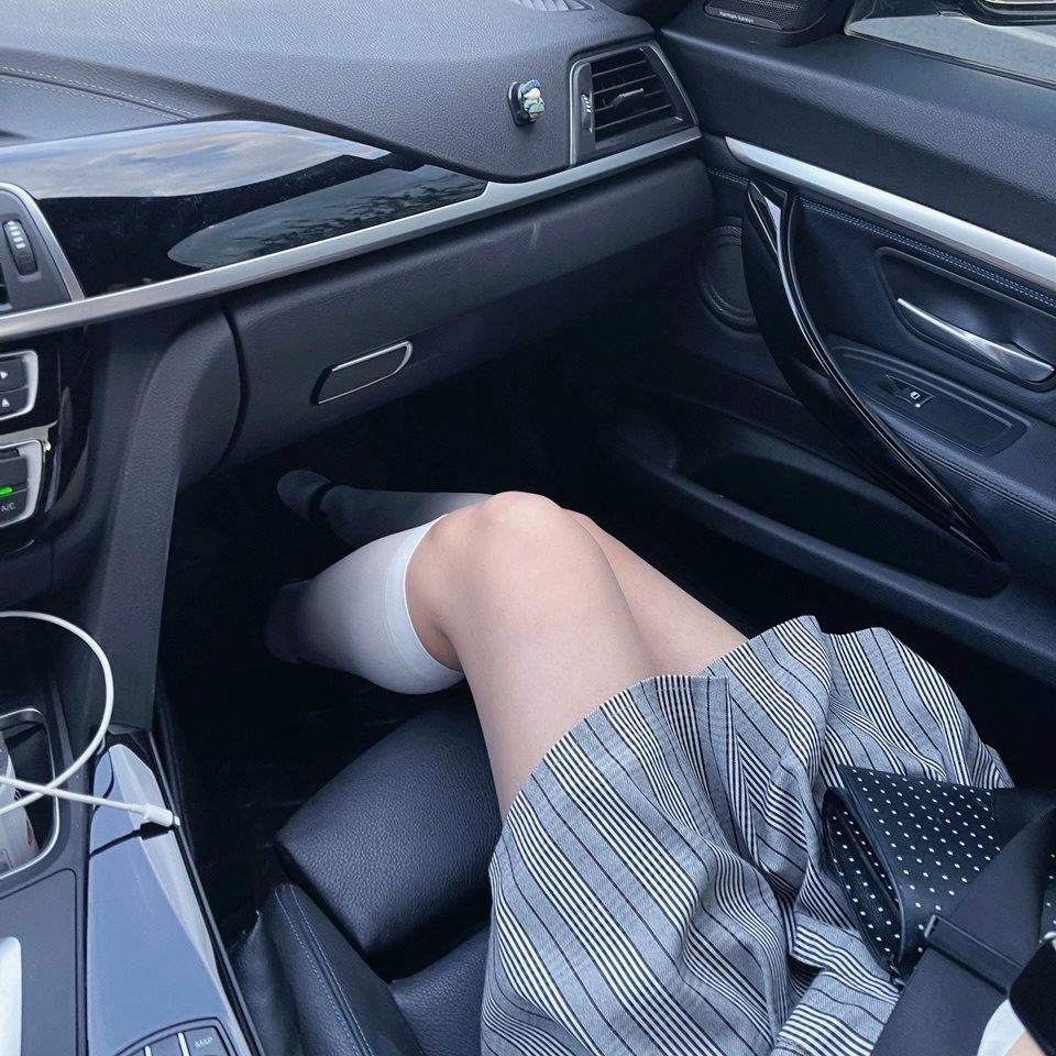 穿着裙子和袜子的女人坐在车里。