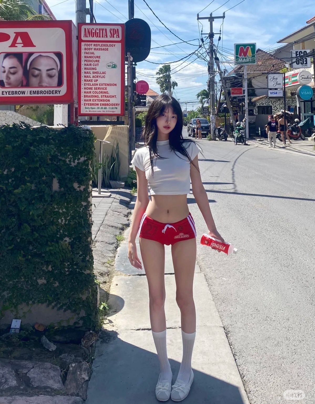 一位穿着红色短裤和一件白色衬衫的女人站在通道上。