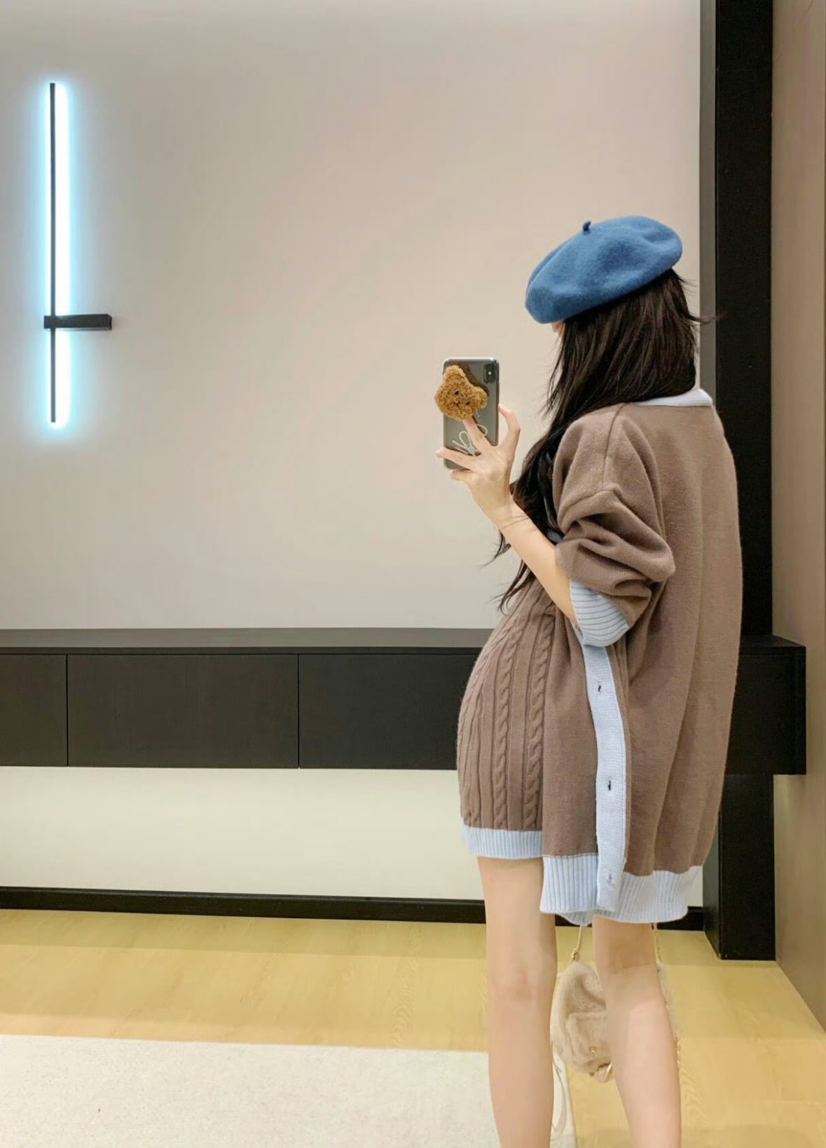 穿着蓝色帽子和棕色外套的女人拍了一张自拍。