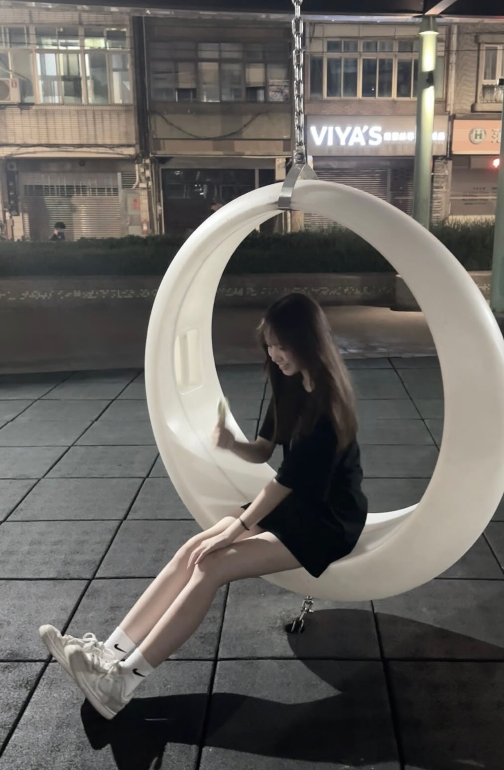 女人坐在白色的椅子上,手里拿着一件绿色的物体。