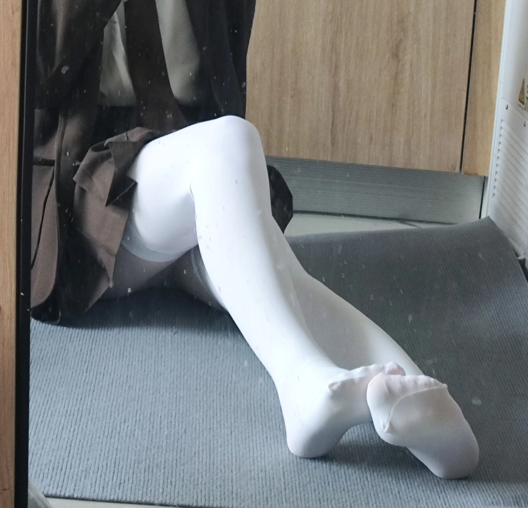 穿着白色袜子和棕色外套的女人坐在地板上。