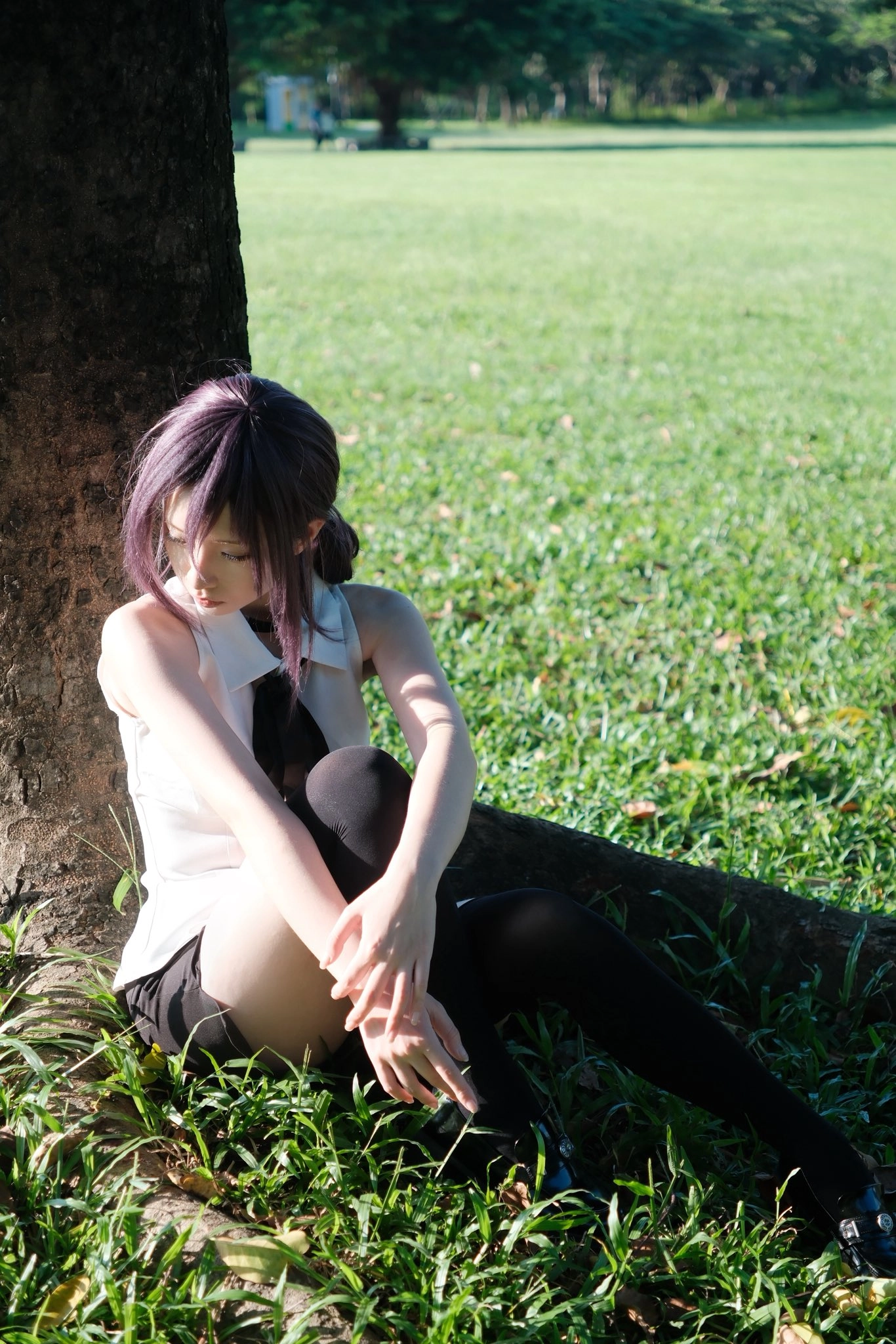 紫色头发的女人坐在草地上。