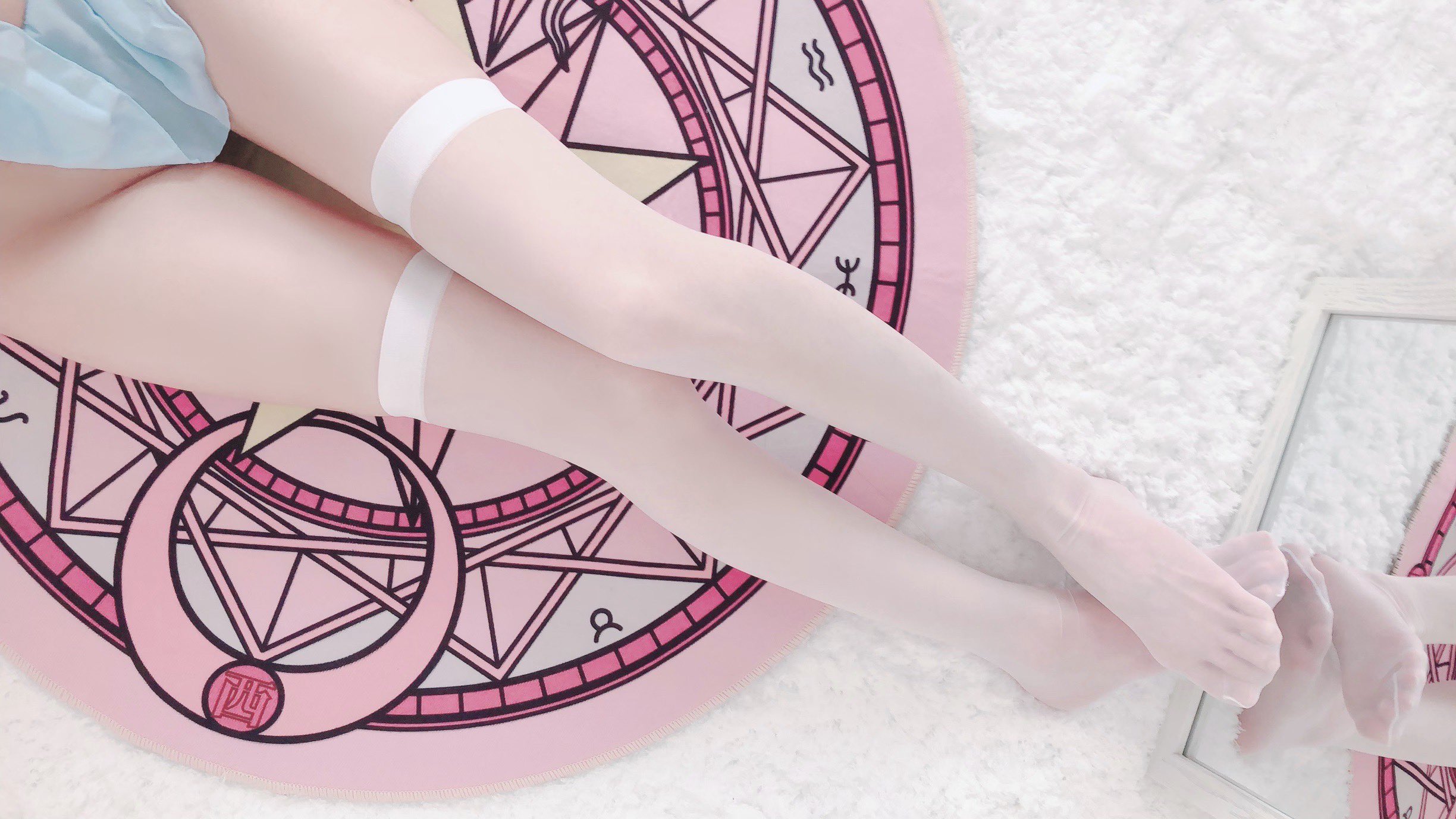 穿白袜的女人躺在一个粉红色和白色的毯子上。