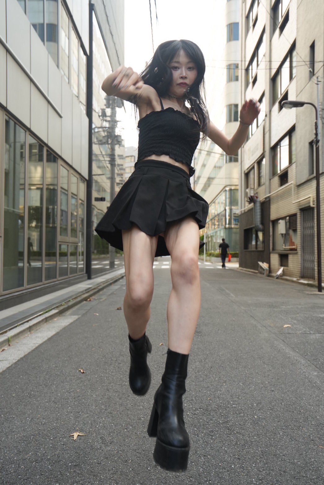 一位穿着黑色短裤和黑靴的女人走在城市街道上。