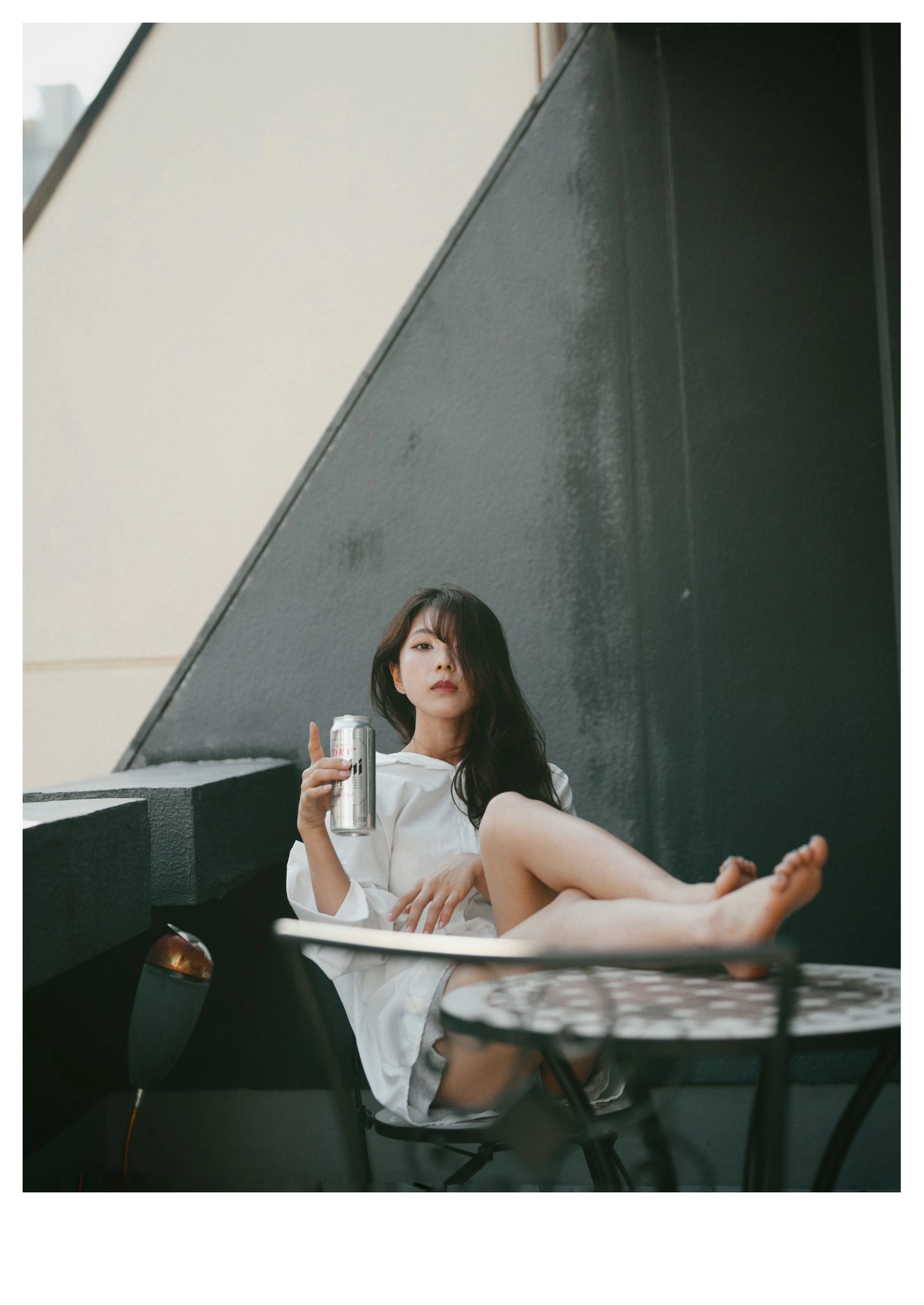 一位穿着白色衣服的女人坐在椅子上,手里拿着一瓶啤酒。