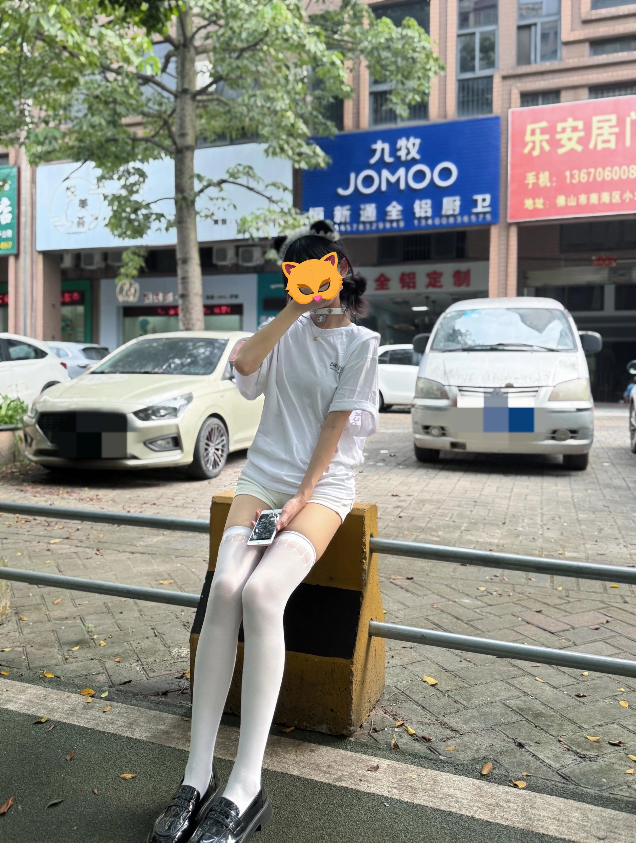 手里拿着手机的女人坐在一张凳子上。