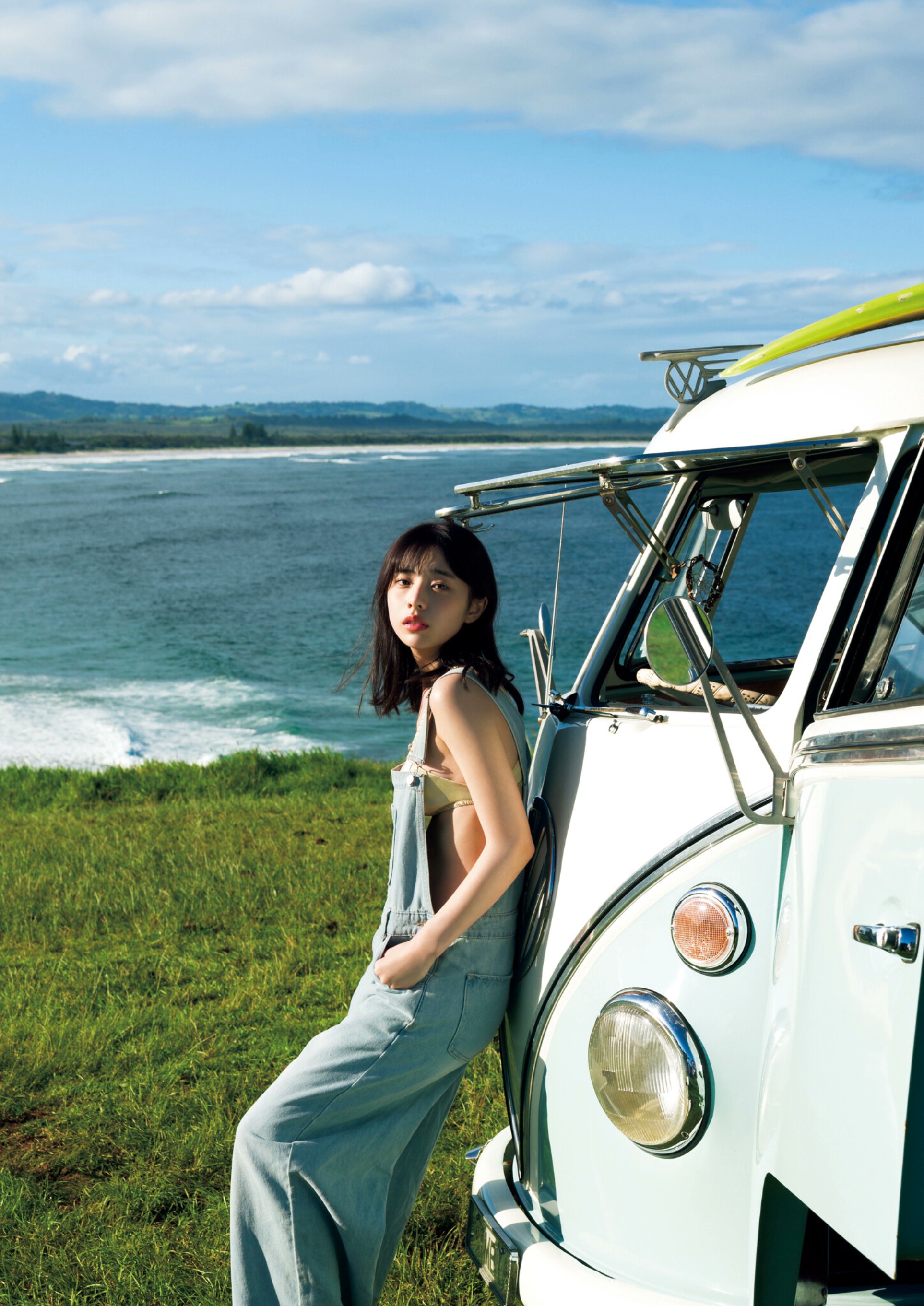 一位穿着蓝色裙子的女人站在一辆时尚大众货车旁边。