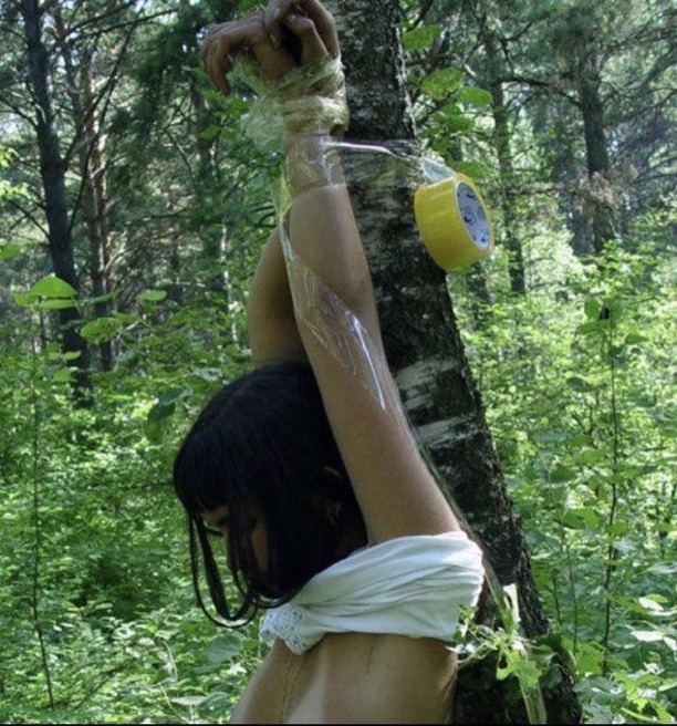 女人在森林里被绑在一棵树上。