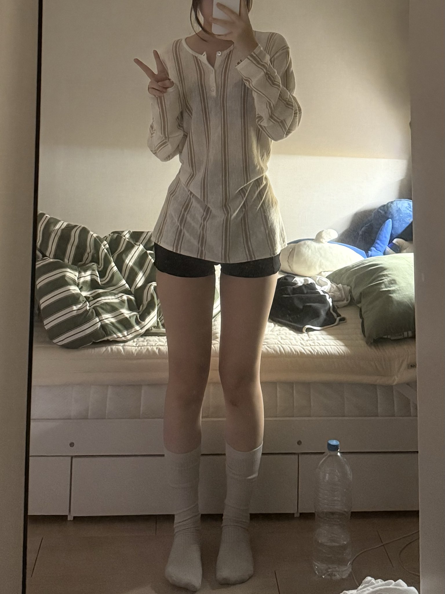 穿着白色衬衫和黑色短裤的女人站在镜子前。