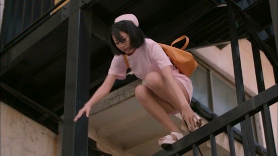 穿着粉红色衣服的女人爬上了一条金属铁路。