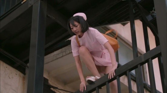 穿着粉红色衣服的女人爬上了一条金属铁路。