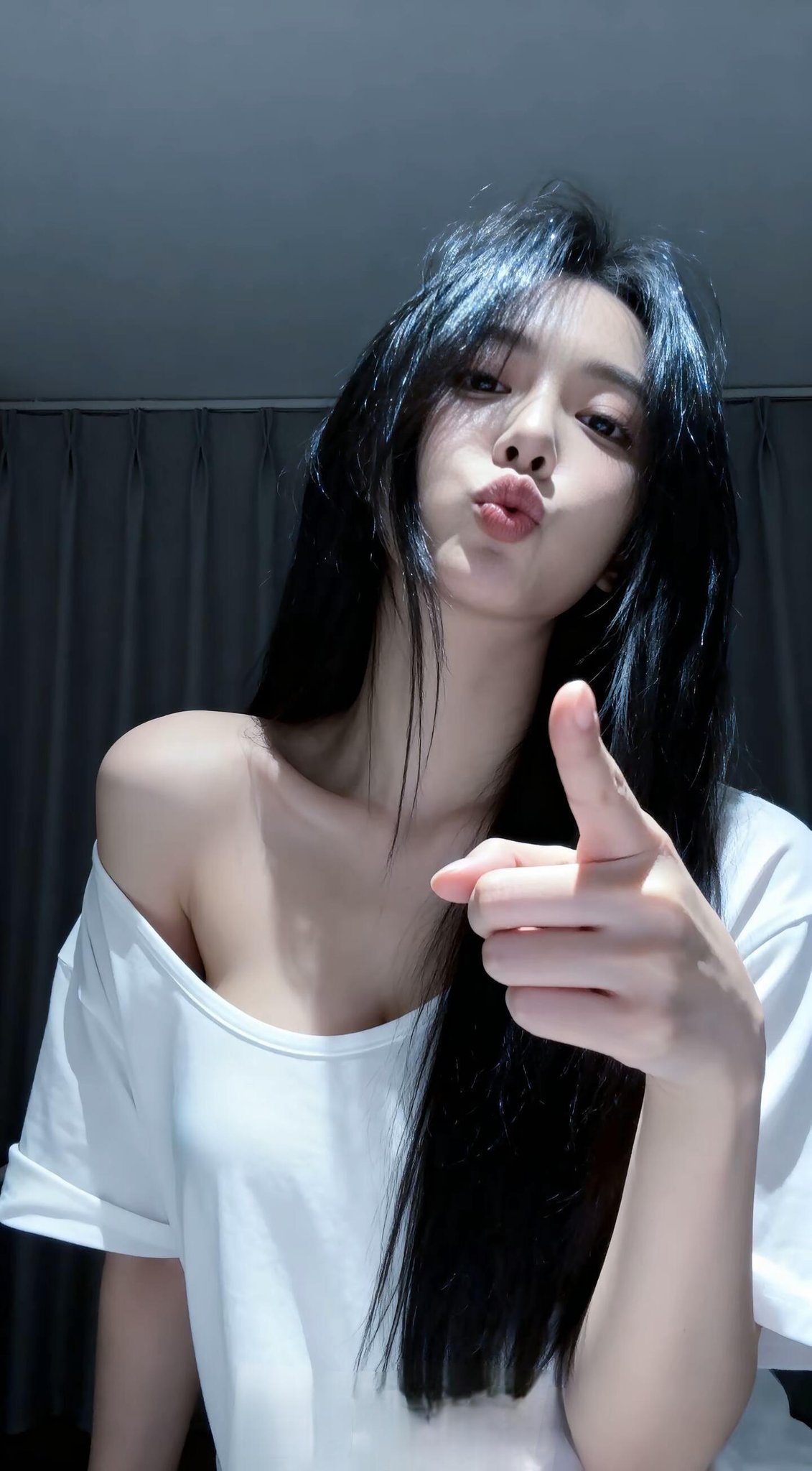 黑头发和白衬衫的女人指向相机。