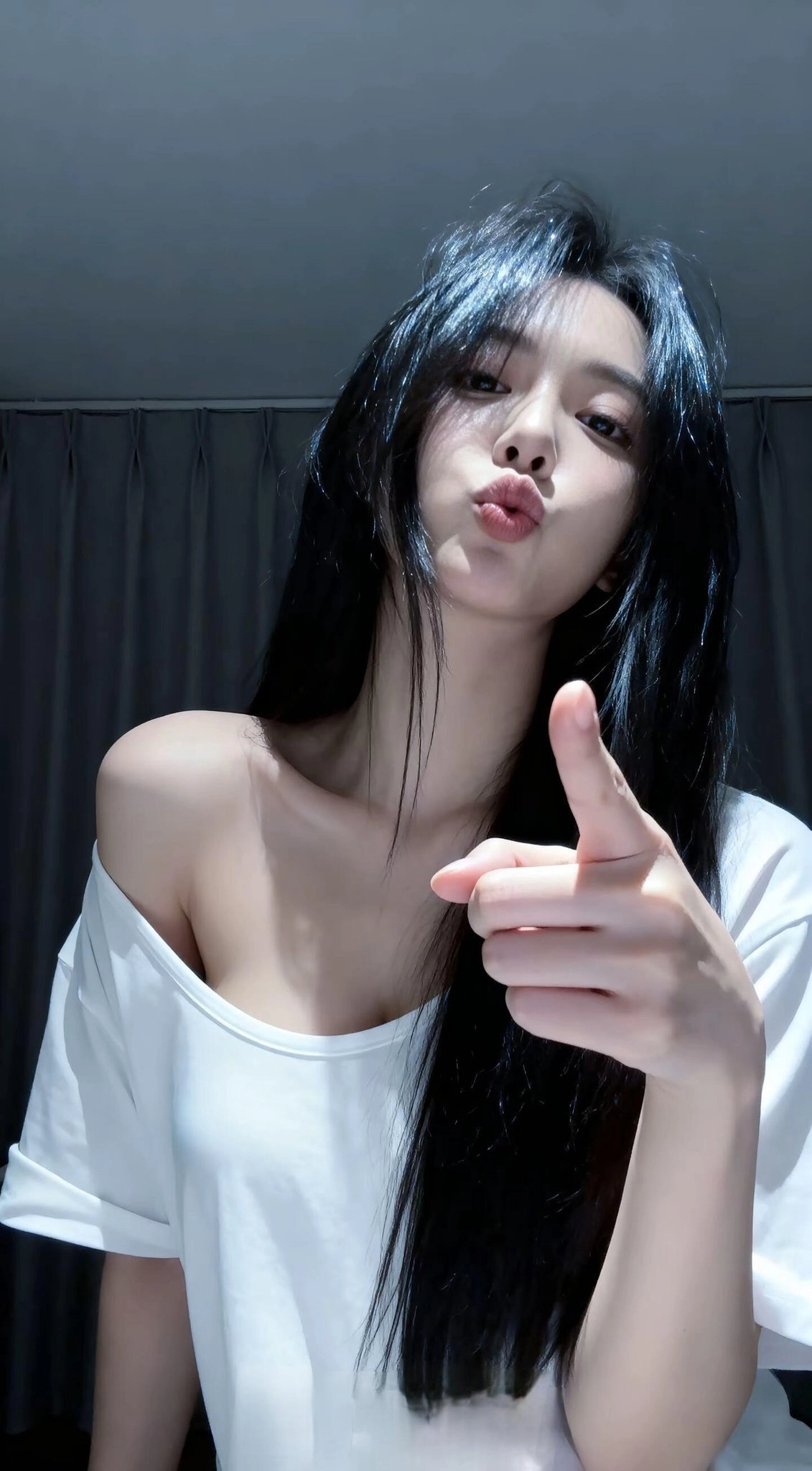 黑头发和白衬衫的女人指向相机。