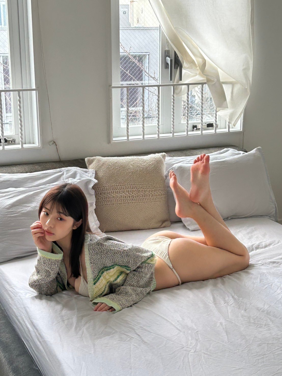 穿着灰色衬衫的女人躺在床上。