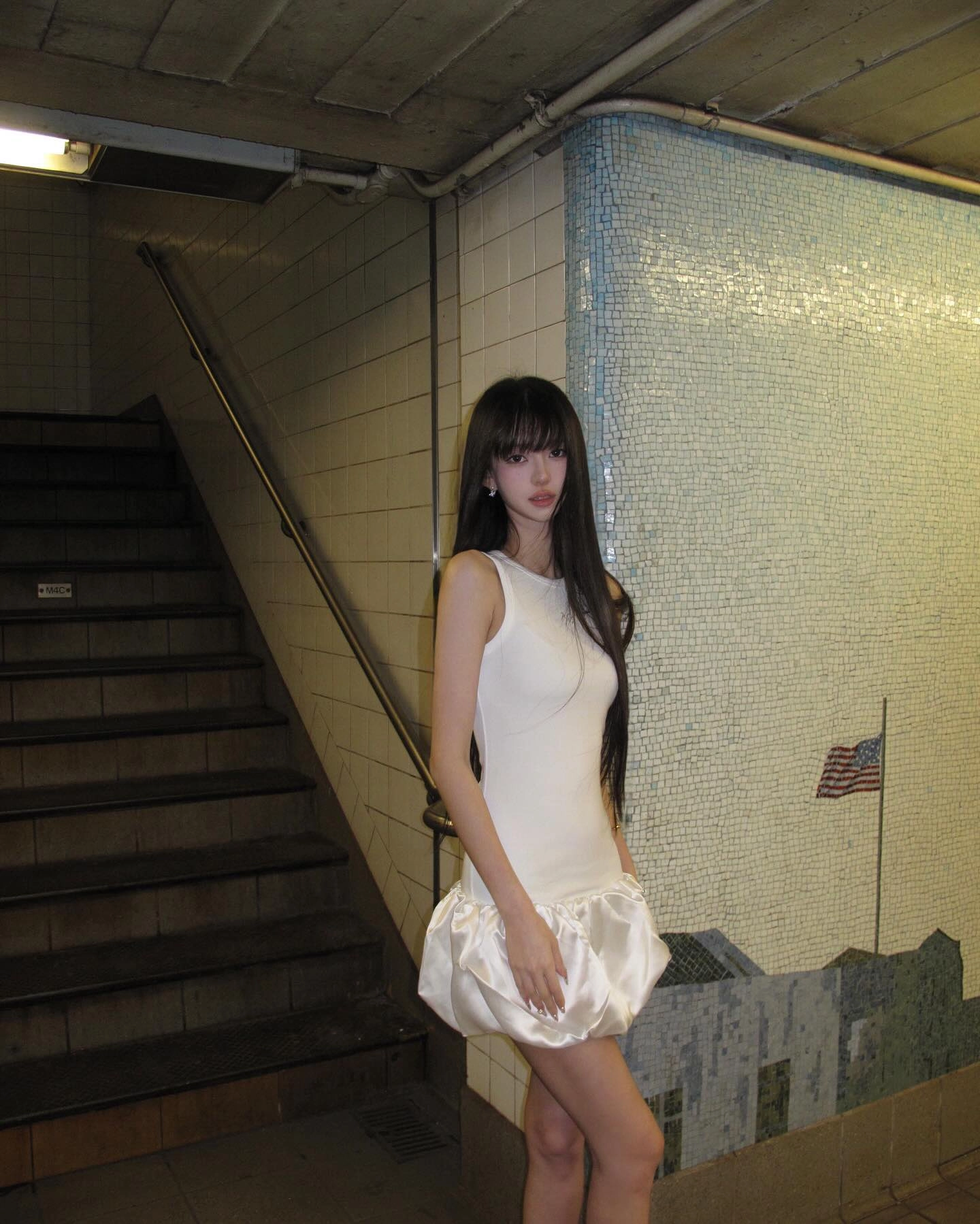 一位穿着白色衣服的女人站在地铁平台上。