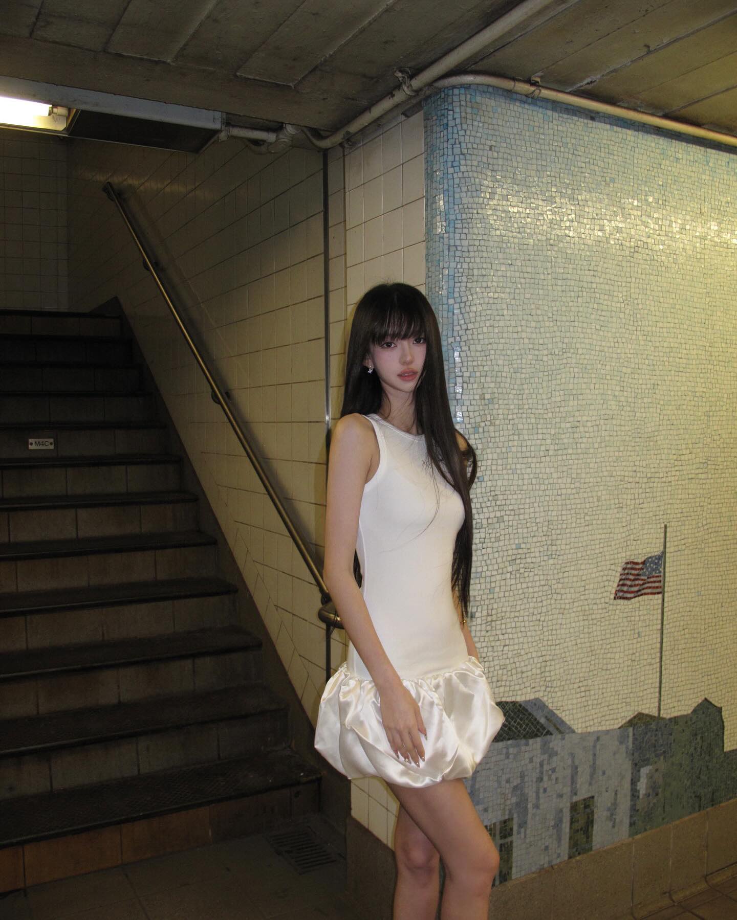 一位穿着白色衣服的女人站在地铁平台上。