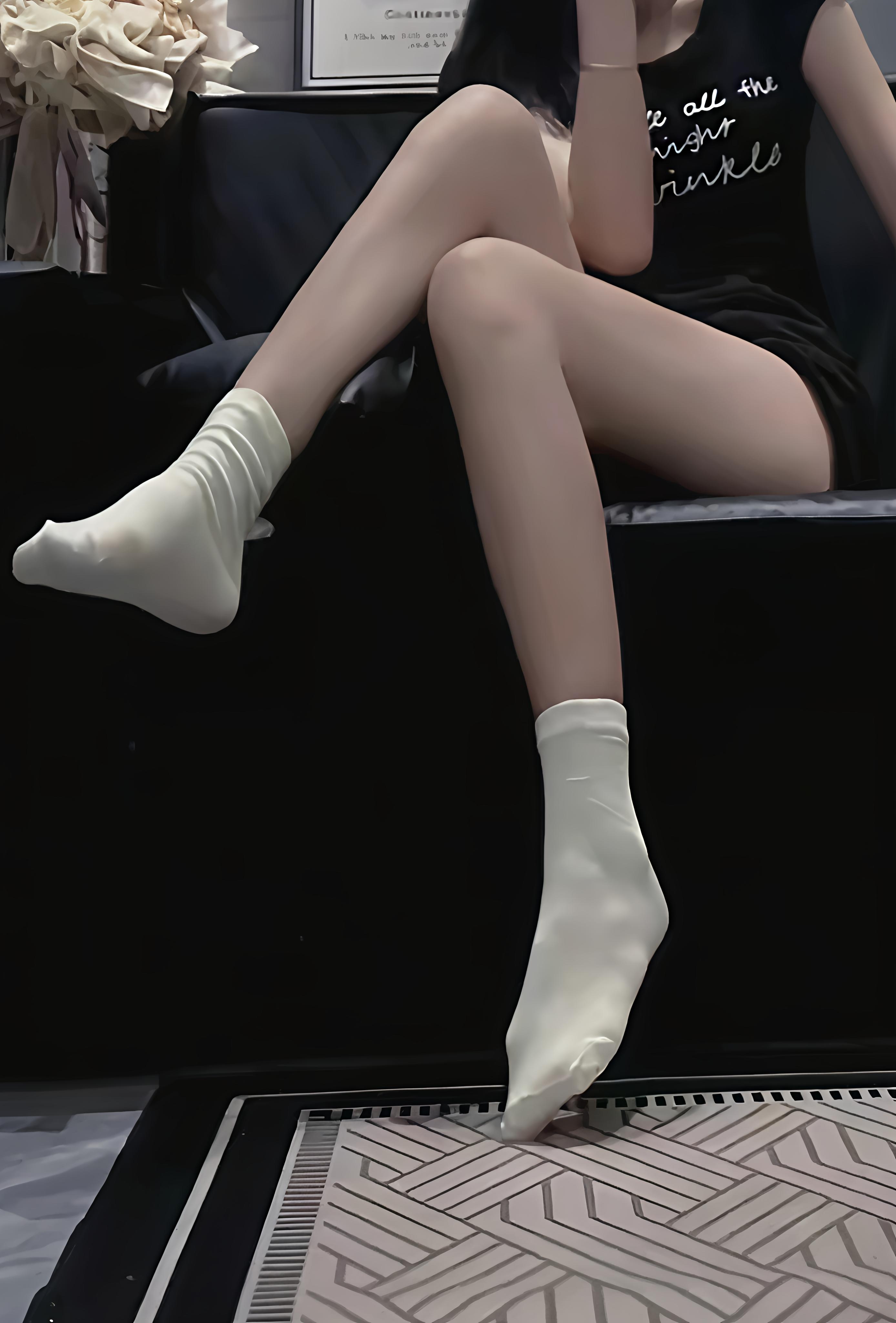 穿着黑色袜子和白色袜子的女人坐在椅子上。